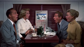Movie still from “White Christmas” (1954), directed by Michael Curtiz – A man and a woman sitting at a table; Medium shot, Low angle