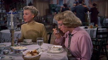 Movie still from “White Christmas” (1954), directed by Michael Curtiz – Two women sitting at a table eating food; Medium shot, Over the shoulder angle