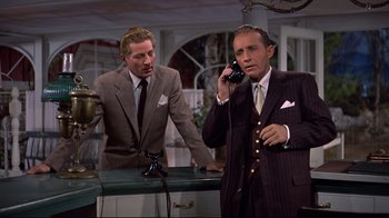 Movie still from “White Christmas” (1954), directed by Michael Curtiz – Two men in suits and ties are talking on a phone; Medium shot, Low angle