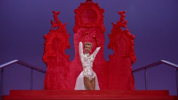 Movie still from “White Christmas” (1954), directed by Michael Curtiz – A woman in a white dress standing in front of a red throne; Wide shot, Low angle