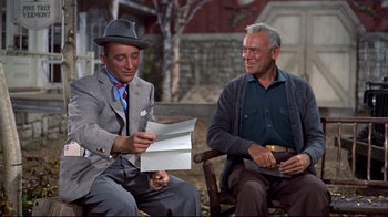 Movie still from “White Christmas” (1954), directed by Michael Curtiz – Two men sitting next to each other holding papers; Medium shot, High angle
