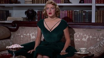 Movie still from “White Christmas” (1954), directed by Michael Curtiz – A woman sitting on top of a couch wearing a green dress; Medium shot, Low angle