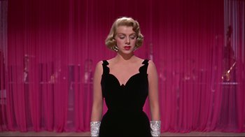 Movie still from “White Christmas” (1954), directed by Michael Curtiz – A woman in a black dress and white gloves; Medium shot, Low angle