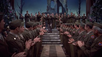 Movie still from “White Christmas” (1954), directed by Michael Curtiz – A group of men standing in front of each other in uniform; Wide shot, High angle