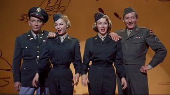 Movie still from “White Christmas” (1954), directed by Michael Curtiz – A group of people standing next to each other in uniforms; Medium shot, Low angle