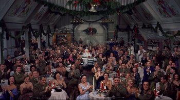 Movie still from “White Christmas” (1954), directed by Michael Curtiz – A large group of people sitting at a table; Wide shot, High angle