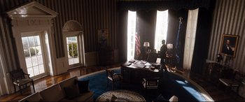 Movie still from “White House Down” (2013), directed by Roland Emmerich – A man standing in front of a desk in a room; Wide shot, Low angle