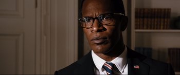 Movie still from “White House Down” (2013), directed by Roland Emmerich – A person wearing glasses and a suit; Close Up shot, Low angle