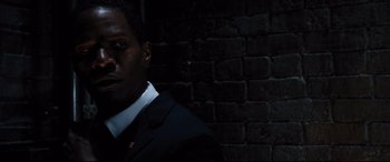 Movie still from “White House Down” (2013), directed by Roland Emmerich – A man in a suit and tie standing in front of a brick wall; Close Up shot, High angle