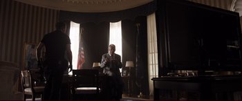 Movie still from “White House Down” (2013), directed by Roland Emmerich – An older man sitting in a chair in front of a flag; Wide shot, Low angle