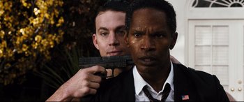 Movie still from “White House Down” (2013), directed by Roland Emmerich – A man holding a gun next to another man in a white shirt; Close Up shot, Over the shoulder angle