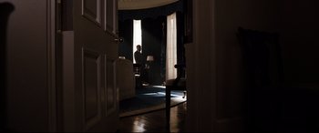 Movie still from “White House Down” (2013), directed by Roland Emmerich – A man standing in a living room looking out a window; Wide shot, Low angle
