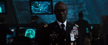 Movie still from “White House Down” (2013), directed by Roland Emmerich – A man in a military uniform standing in front of a television; Medium shot, Over the shoulder angle