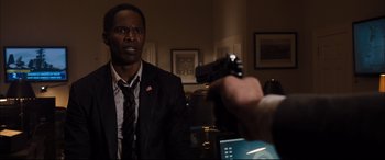 Movie still from “White House Down” (2013), directed by Roland Emmerich – A man in a suit and tie holding a gun; Close Up shot, Over the shoulder angle