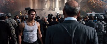Movie still from “White House Down” (2013), directed by Roland Emmerich – A group of people standing around a building with a camera; Medium shot, Over the shoulder angle