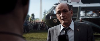 Movie still from “White House Down” (2013), directed by Roland Emmerich – An older man in a suit and tie looking at the camera; Close Up shot, Over the shoulder angle