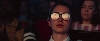 Movie still from “White Noise” (2022), directed by Noah Baumbach – A person wearing glasses and a white shirt; Close Up shot, Low angle