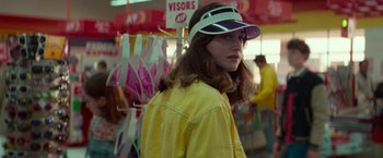 Movie still from “White Noise” (2022), directed by Noah Baumbach – A woman wearing a yellow jacket and a visor; Close Up shot, Over the shoulder angle