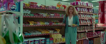 Movie still from “White Noise” (2022), directed by Noah Baumbach – A woman standing next to shelves in a grocery store; Wide shot, Low angle