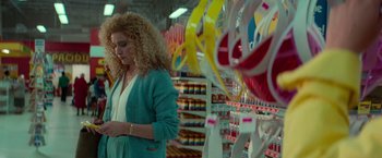 Movie still from “White Noise” (2022), directed by Noah Baumbach – A woman standing in front of shelves in a grocery store; Medium shot, Over the shoulder angle