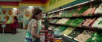 Movie still from “White Noise” (2022), directed by Noah Baumbach – A young girl is pushing a shopping cart in a grocery store; Medium shot, Over the shoulder angle