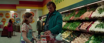 Movie still from “White Noise” (2022), directed by Noah Baumbach – A man is pushing a shopping cart in a grocery store; Medium shot, Over the shoulder angle