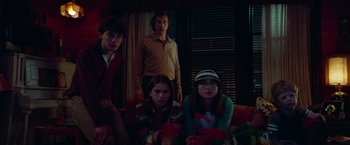 Movie still from “White Noise” (2022), directed by Noah Baumbach – Three people sitting on a couch in front of a window; Medium shot, Low angle