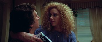 Movie still from “White Noise” (2022), directed by Noah Baumbach – A woman with curly hair is holding a book; Close Up shot, Over the shoulder angle