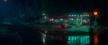 Movie still from “White Noise” (2022), directed by Noah Baumbach – A car parked in front of a gas station at night; Extreme Wide shot, High angle