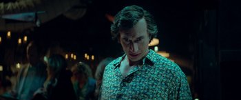 Movie still from “White Noise” (2022), directed by Noah Baumbach – A man in a green shirt is looking at the camera; Medium shot, Low angle