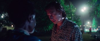 Movie still from “White Noise” (2022), directed by Noah Baumbach – A man in a patterned shirt talking to another man in front of a tree; Close Up shot, Over the shoulder angle