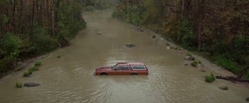 Movie still from “White Noise” (2022), directed by Noah Baumbach – A red suv is driving through a flooded river; Extreme Wide shot, High angle