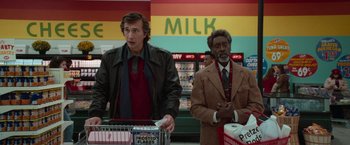 Movie still from “White Noise” (2022), directed by Noah Baumbach – Two men standing next to each other in a grocery store; Medium shot, Over the shoulder angle