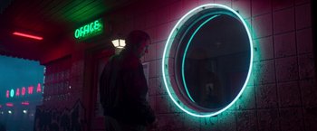 Movie still from “White Noise” (2022), directed by Noah Baumbach – A man standing in front of a round mirror; Wide shot, Low angle