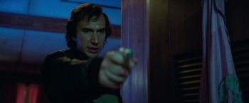 Movie still from “White Noise” (2022), directed by Noah Baumbach – A man holding a remote control in his hand; Close Up shot, Low angle