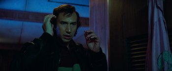 Movie still from “White Noise” (2022), directed by Noah Baumbach – A man holding a cell phone up to his ear; Close Up shot, Low angle