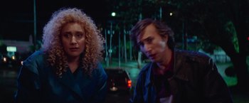 Movie still from “White Noise” (2022), directed by Noah Baumbach – A man and a woman sitting next to each other on the street; Close Up shot, High angle