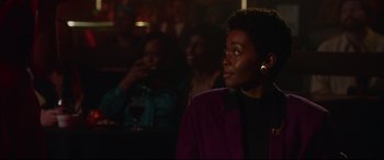 Movie still from “Whitney Houston: I Wanna Dance with Somebody” (2022), directed by Kasi Lemmons – A woman in a purple jacket looking up at a crowd; Close Up shot, Over the shoulder angle