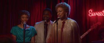Movie still from “Whitney Houston: I Wanna Dance with Somebody” (2022), directed by Kasi Lemmons – A couple of people that are singing on a stage; Medium shot, Low angle