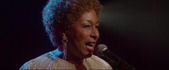 Movie still from “Whitney Houston: I Wanna Dance with Somebody” (2022), directed by Kasi Lemmons – A person singing on a microphone; Close Up shot, Low angle