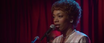 Movie still from “Whitney Houston: I Wanna Dance with Somebody” (2022), directed by Kasi Lemmons – A woman is singing into a microphone in front of a crowd; Close Up shot, Over the shoulder angle