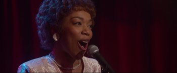Movie still from “Whitney Houston: I Wanna Dance with Somebody” (2022), directed by Kasi Lemmons – A woman singing into a microphone on a stage; Close Up shot, Low angle