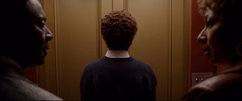 Movie still from “Whitney Houston: I Wanna Dance with Somebody” (2022), directed by Kasi Lemmons – A person with curly hair standing in front of a wall; Medium shot, Low angle