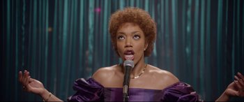 Movie still from “Whitney Houston: I Wanna Dance with Somebody” (2022), directed by Kasi Lemmons – A woman in a purple dress holding a microphone; Close Up shot, Low angle