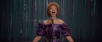 Movie still from “Whitney Houston: I Wanna Dance with Somebody” (2022), directed by Kasi Lemmons – A woman in a purple dress singing into a microphone; Medium shot, Low angle