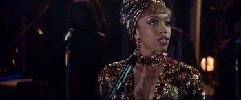 Movie still from “Whitney Houston: I Wanna Dance with Somebody” (2022), directed by Kasi Lemmons – A person with a microphone on a stage; Close Up shot, Over the shoulder angle