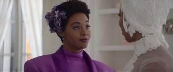 Movie still from “Whitney Houston: I Wanna Dance with Somebody” (2022), directed by Kasi Lemmons – A woman in a purple dress with purple flowers in her hair; Close Up shot, Over the shoulder angle