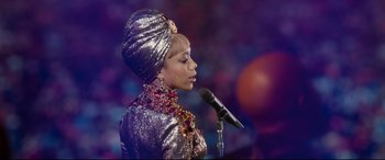 Movie still from “Whitney Houston: I Wanna Dance with Somebody” (2022), directed by Kasi Lemmons – A woman in a silver outfit is holding a microphone; Medium shot, Low angle