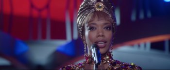 Movie still from “Whitney Houston: I Wanna Dance with Somebody” (2022), directed by Kasi Lemmons – A person holding a microphone; Close Up shot, Over the shoulder angle