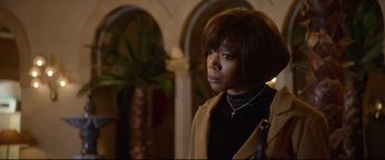 Movie still from “Whitney Houston: I Wanna Dance with Somebody” (2022), directed by Kasi Lemmons – A woman in a black top and brown jacket; Close Up shot, Over the shoulder angle